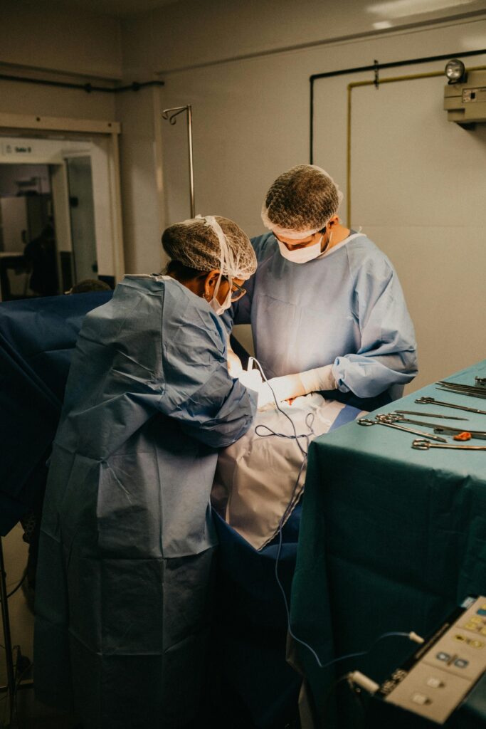 pexels-photo-3259624-3259624 Two surgeons in an operating room conducting surgery under bright lights.